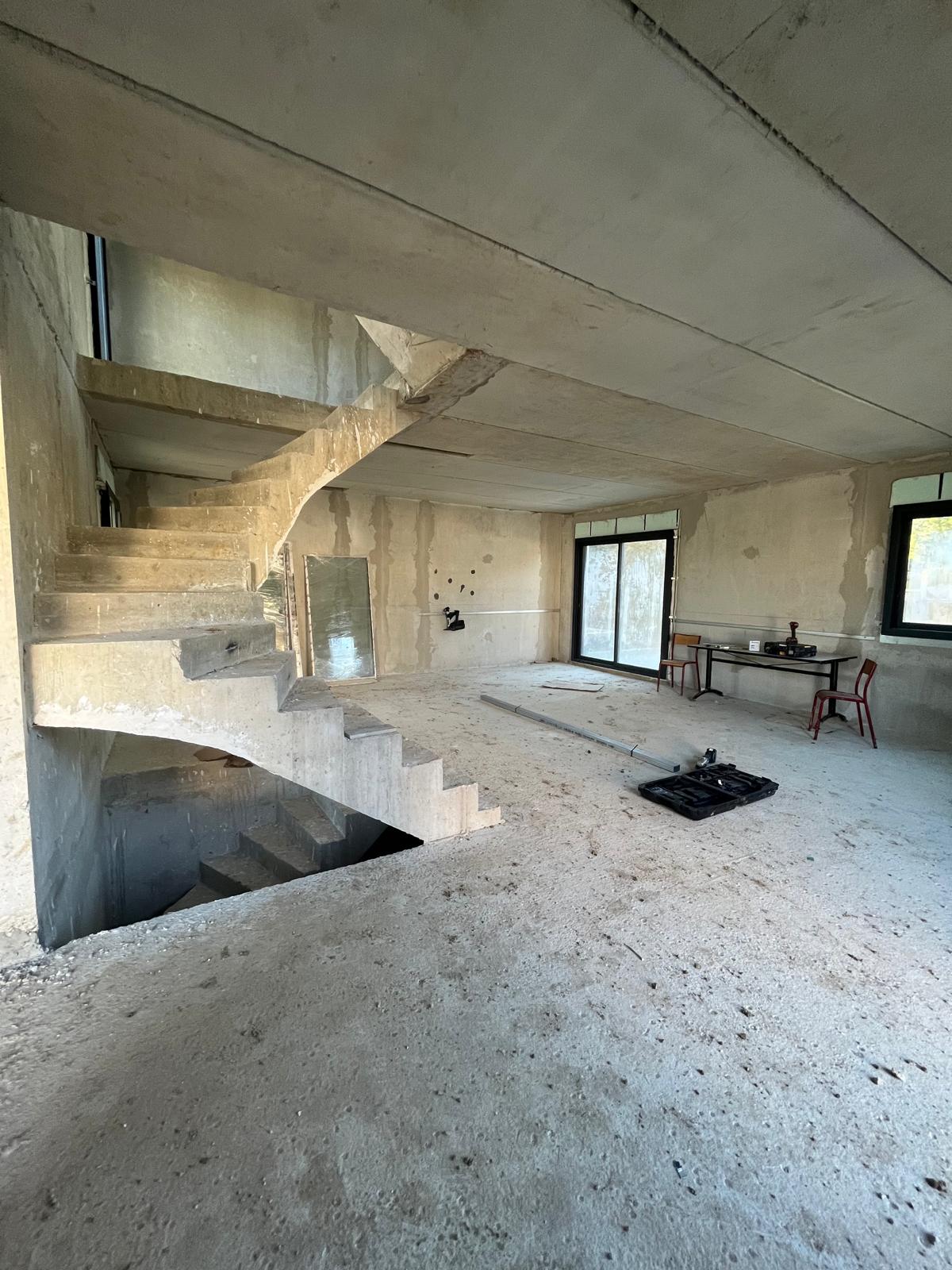 Grand espace en béton brut avant pose des cloisons — escalier et baies vitrées, Bussy-Saint-Martin (77)