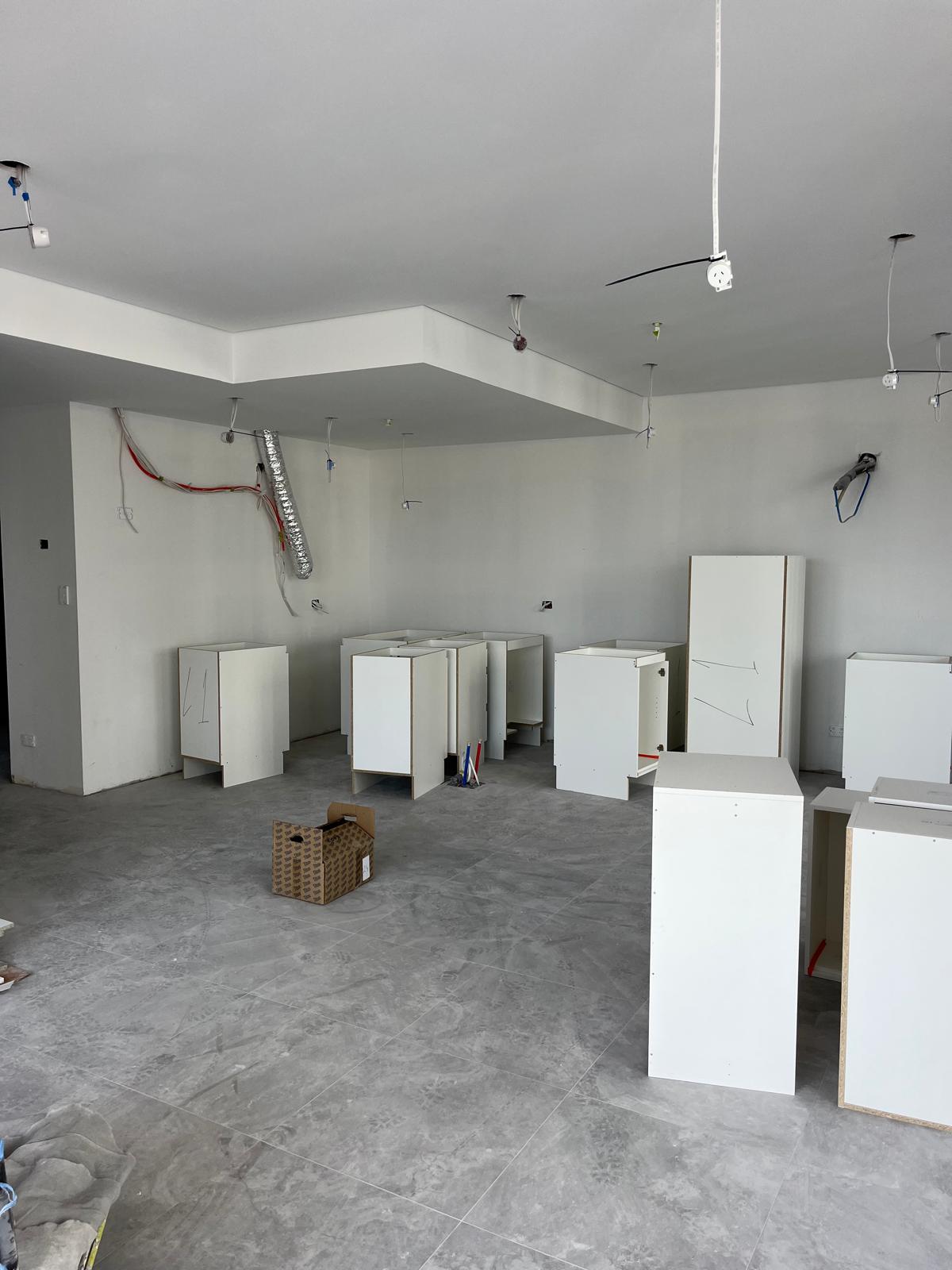 Pose cuisine Sydney Australie — caissons bas blancs implantés au sol, grande cuisine ouverte en cours d'installation