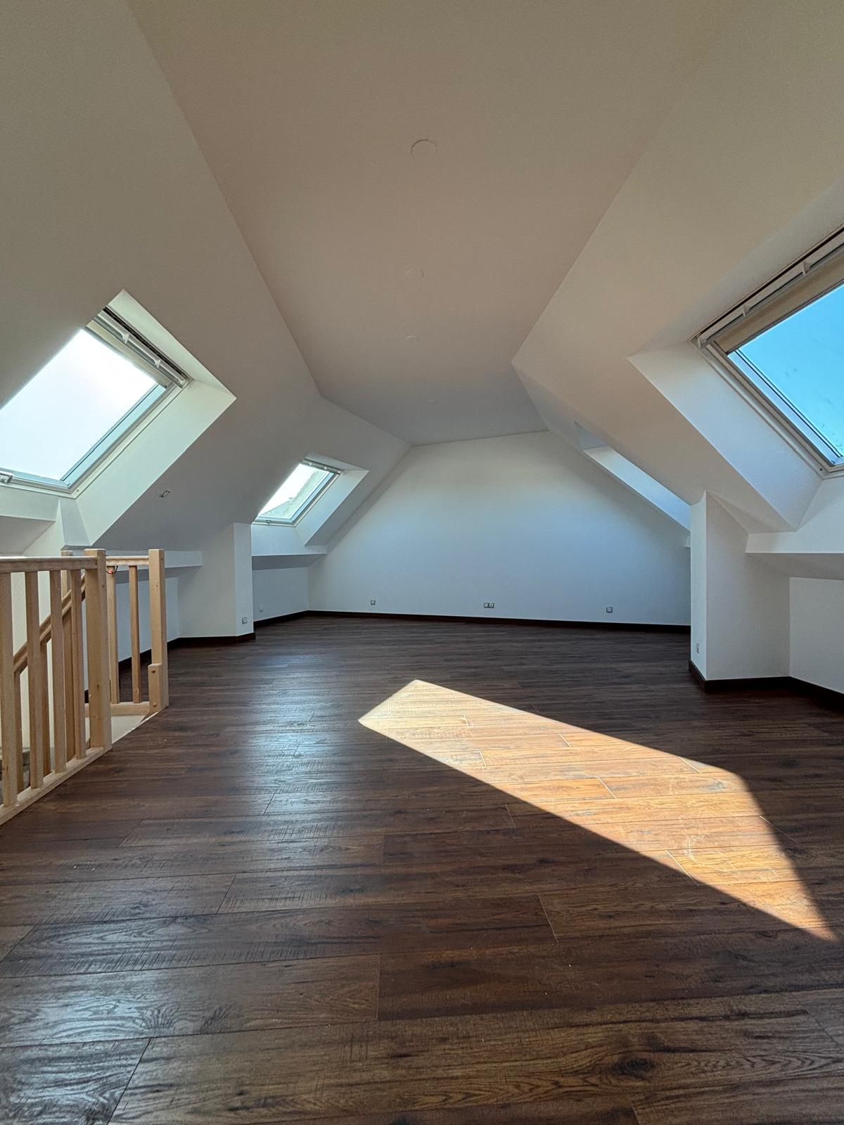 Comble aménagé — vue depuis le fond, parquet flottant bois foncé et velux, Magny-le-Hongre (77)