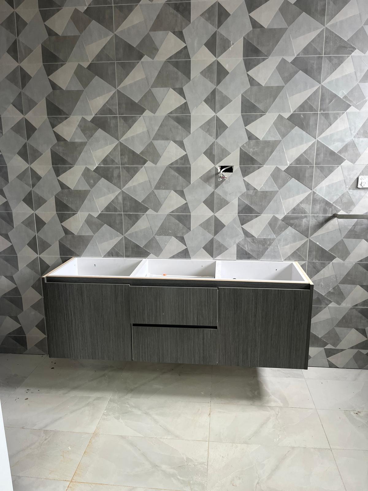 Salle de bain Champigny-sur-Marne pendant rénovation — faïence décorative géométrique grise, meuble double vasque suspendu en cours de pose