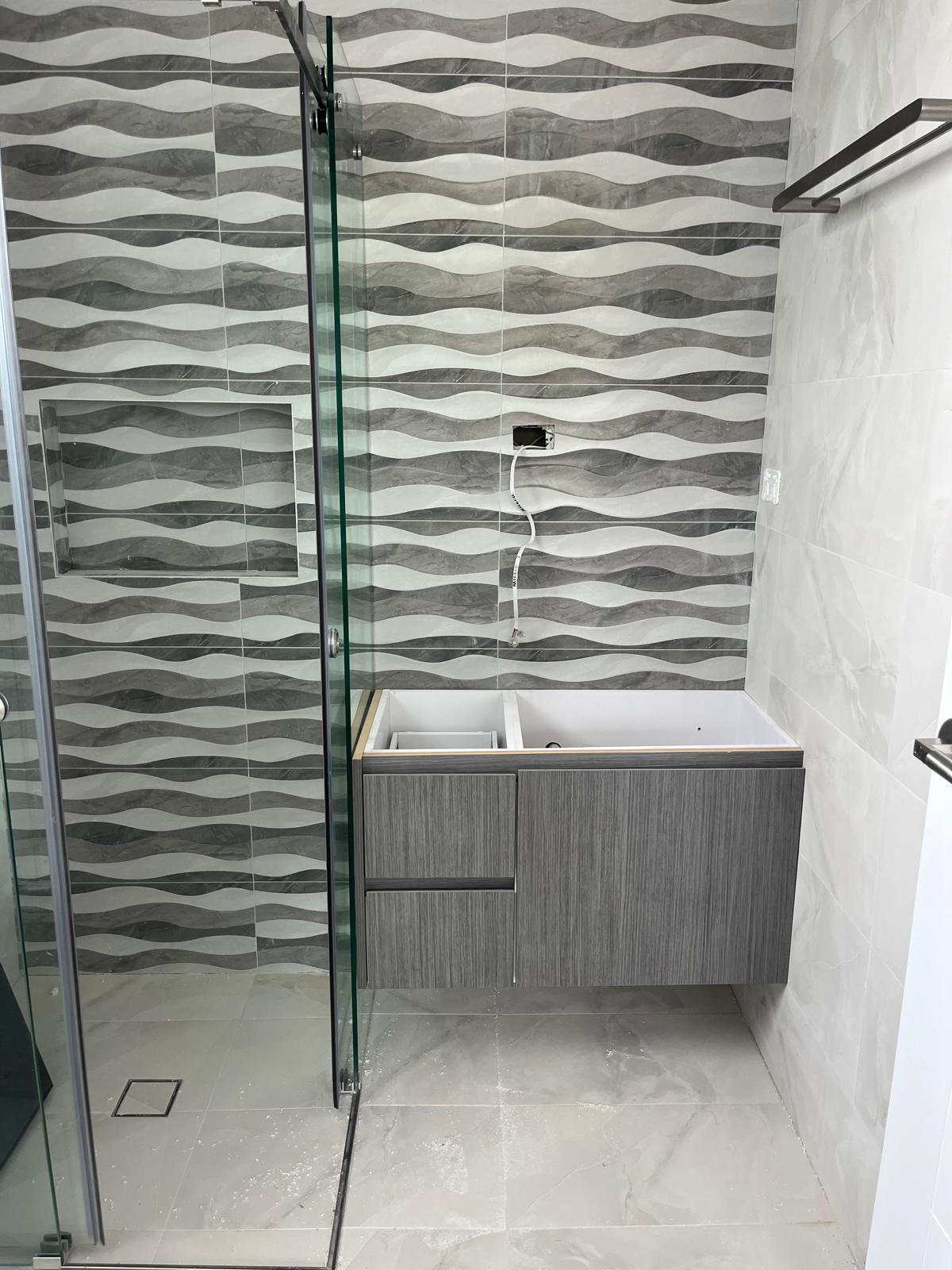 Salle de bain Champigny-sur-Marne pendant rénovation — paroi vitrée douche italienne, faïence vague grise, sol marbre blanc