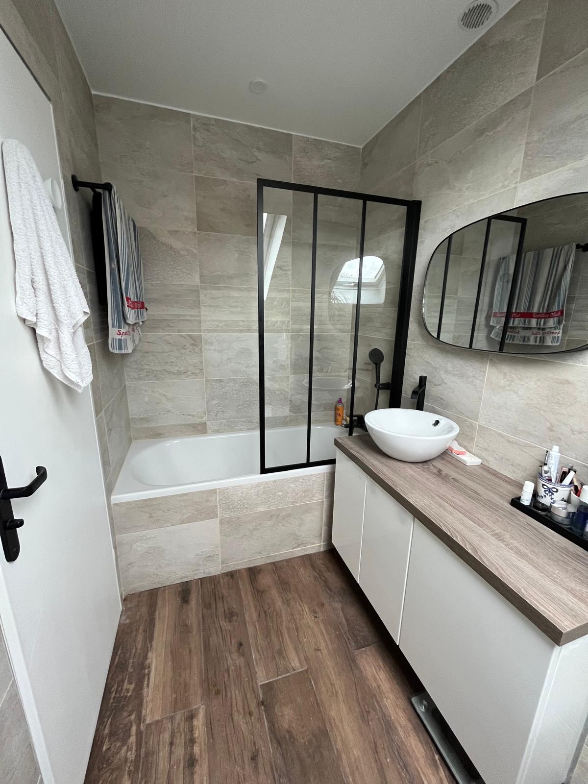 Salle de bain mansardée après rénovation — baignoire paroi verrière, parquet imitation bois, meuble vasque, Collégien (77)