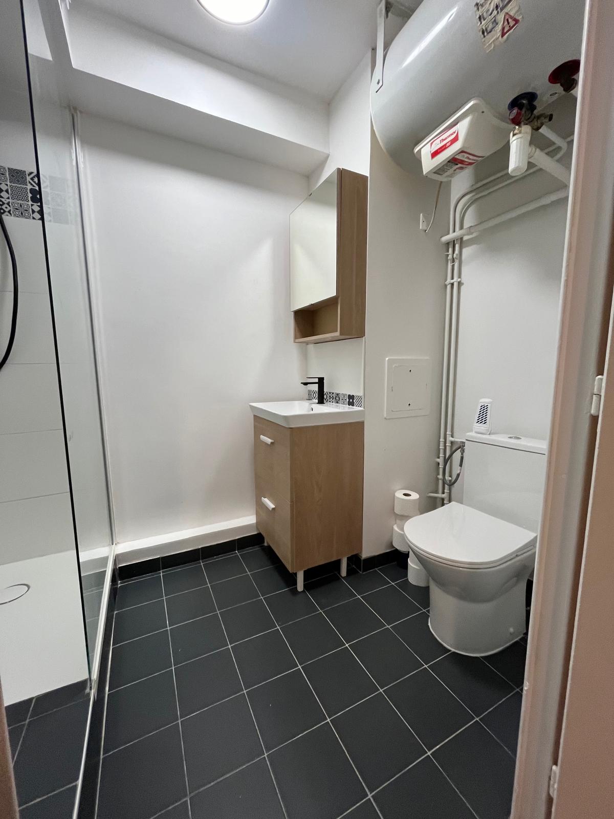 Salle de bain après rénovation — vue d'ensemble douche, WC suspendu et chauffe-eau, studio locatif Noisy-le-Grand (93)